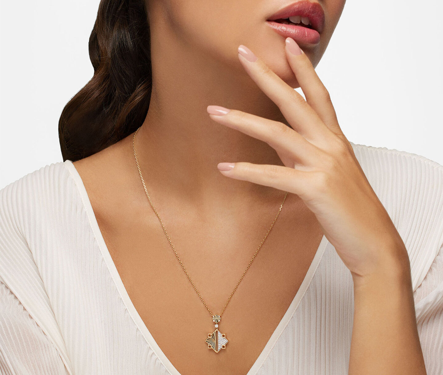 A woman wearing a Birks Muse diamond and gold drop necklace.